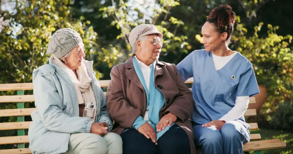 A compassionate caregiver warmly interacting with a smiling elderly patient at home.